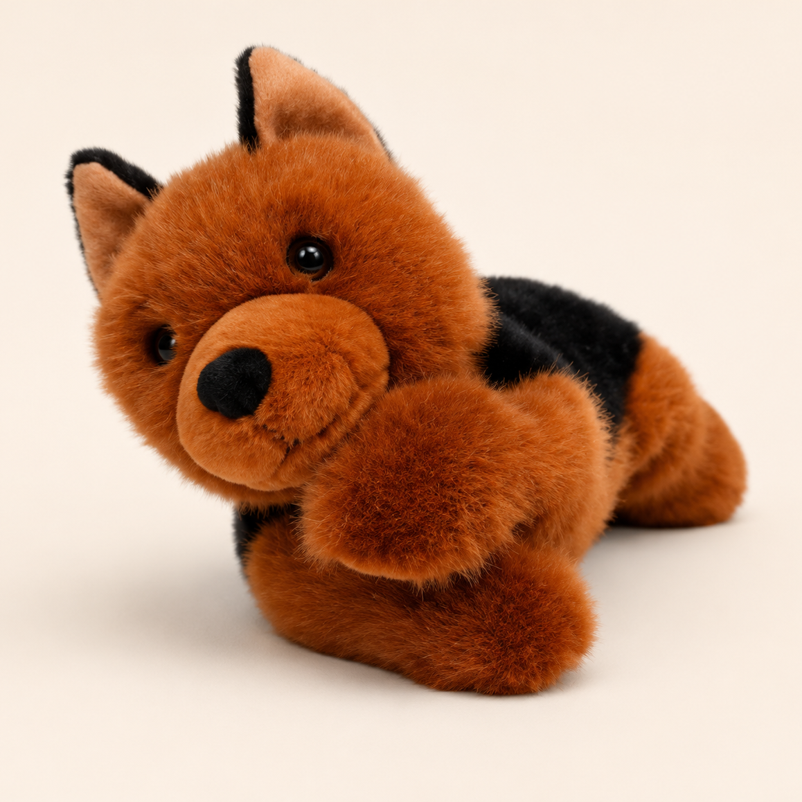 A plush dog toy with fluffy brown fur, black patches on its back and ears, and a black nose, photographed on a plain light beige background.