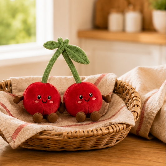 Cherries Besitos plush toy duo displayed in a woven basket on an oak kitchen table beside fresh cherries in a warm Scandinavian-inspired kitchen Plushies South Africa
